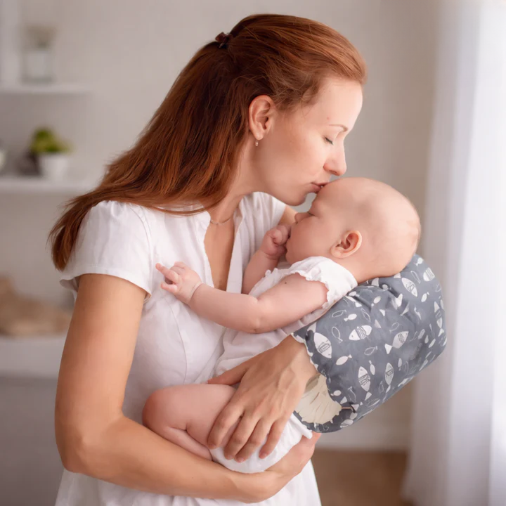 Mother holding baby with gray Arm-Stillkissen nursing pillow in home setting