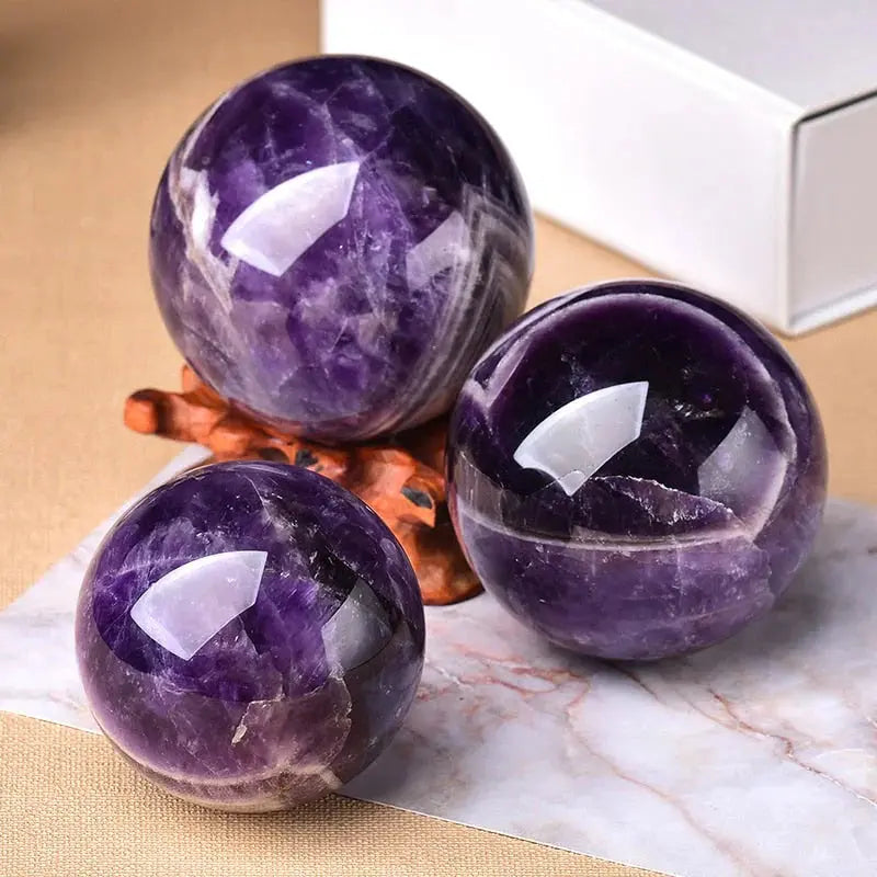 Drei Amethystkugeln handpoliert mit Holzständer und violetten Kristallformationen