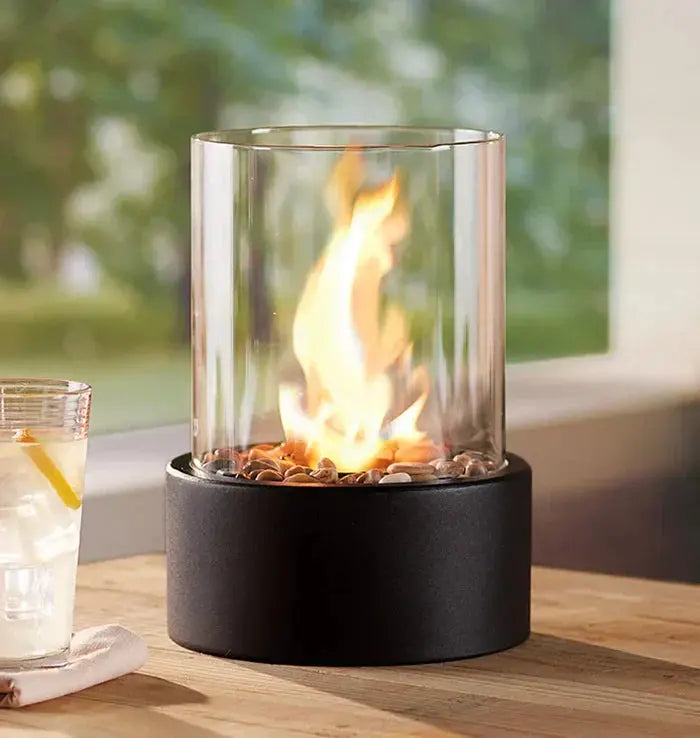 Tischfeuer-Laterne with live flame on outdoor table next to beverage